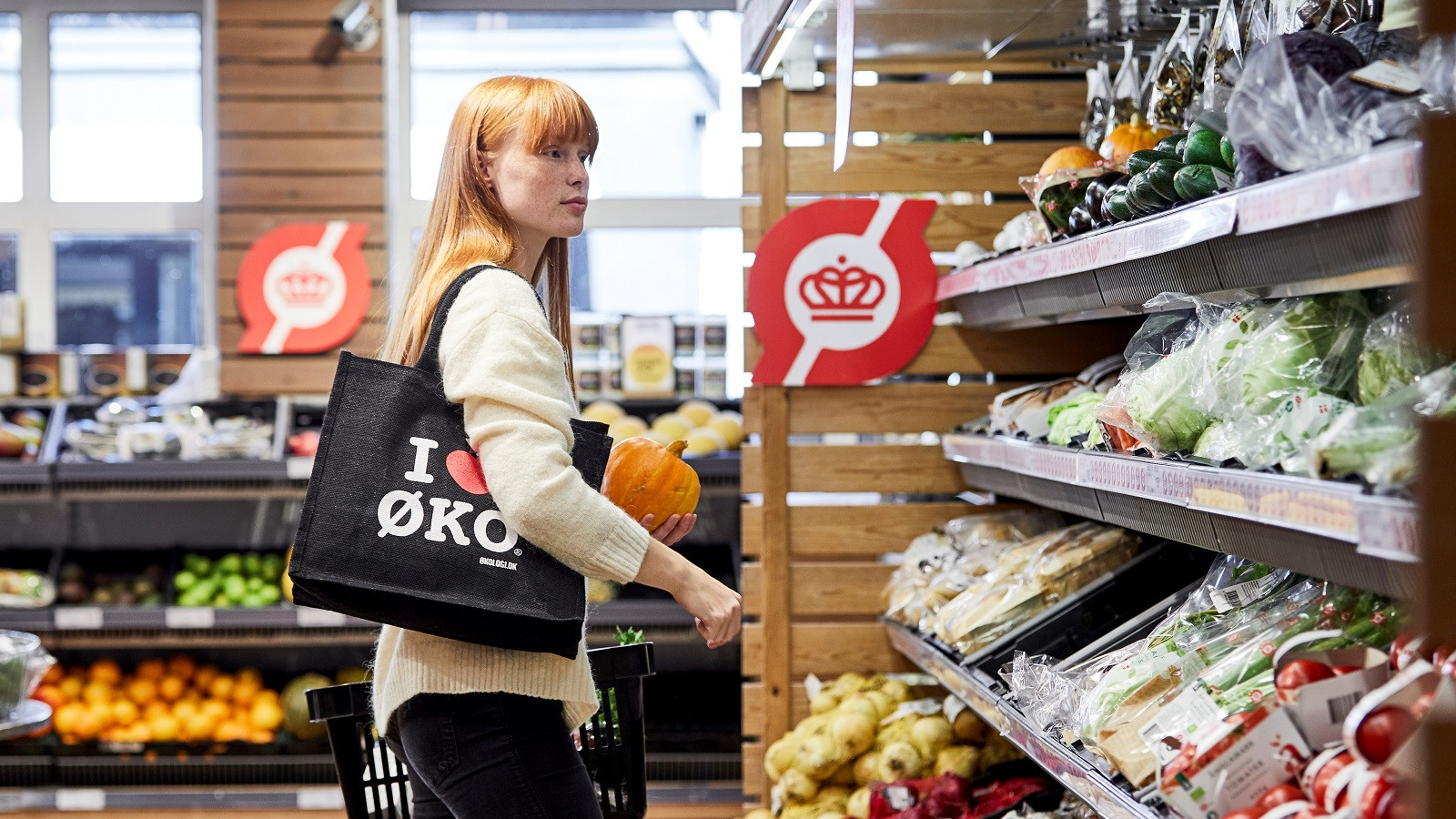 Ung kvinde køber ind i grøntafdeling i supermarked